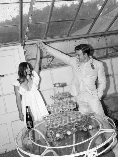 Bride and groom cheering at their champagne tower during their California wedding in La Jolla.