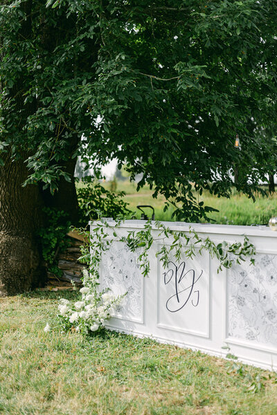 A white bar with floral inserts under a green tree that shows a logo design representing full service design and calligraphy by Life in Letters.