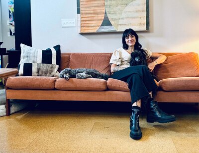 Arianna sits on a couch with her two poodles.