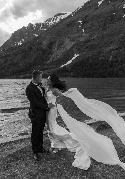 glacier national park elopement with lake and mountain views with her dress blowing in the wind