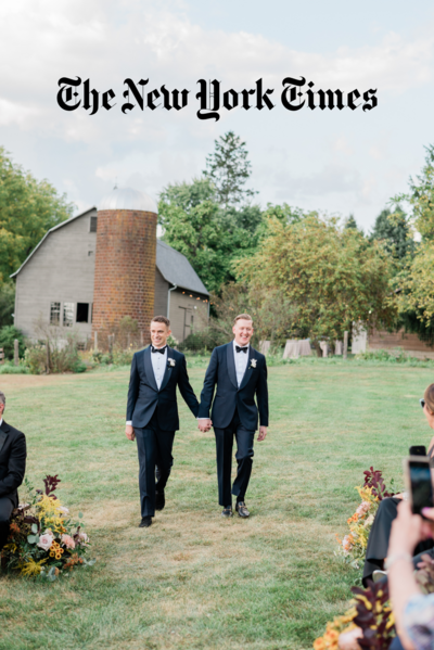 Two grooms hold hands as they walk down the aisle
