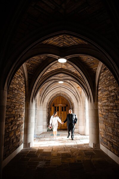 Couple holding hands and walking through historic arches at Scarritt Bennett Center in Nashville
