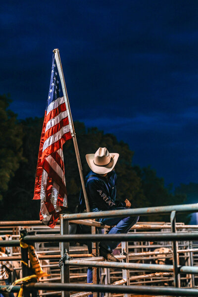 Cowboy Lincoln county Fair sitting on fence near flag