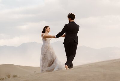 Couple holding hands and spinning around at the sand dunes of Death Valley