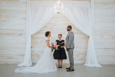 Mixed race couple gets married under a drapery arbor at an elegant Nashville barn venue