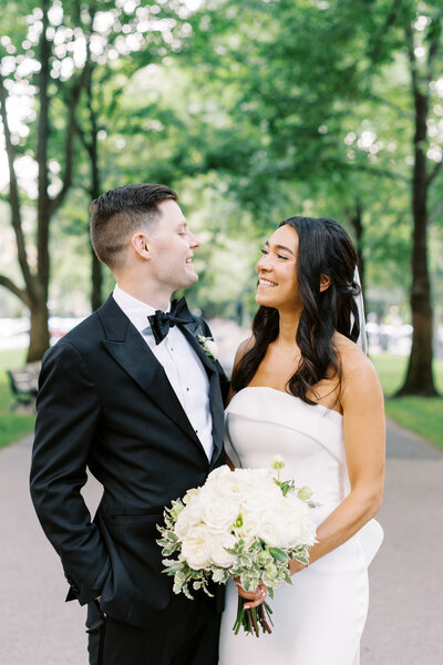 bride and groom stop mid-way down the flower-lined aisle to dip and kiss while guests smile and clap.