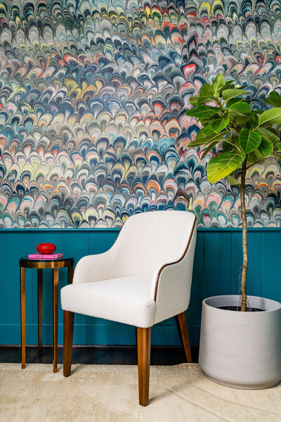 Reading nook with white chair, fiddle fig leaf tree and colourful wallpaper