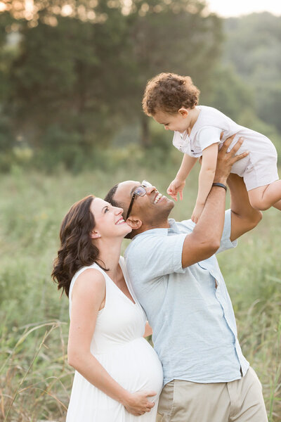 Parents smile and play with son during outdoor maternity photo shoot at park with Julie Brock Photography in Louisville KY