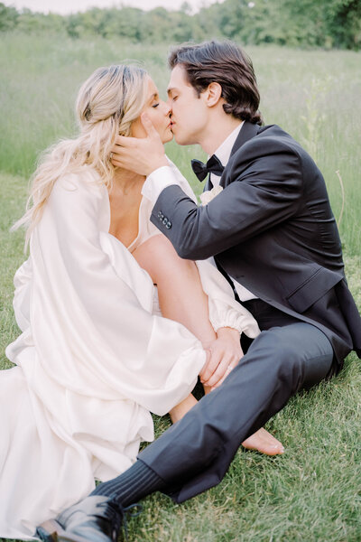 Newport Rhode Island Wedding Photographer Serving RI, Boston, Charleston, and New England Areas | Deirdre Photography | Deirdre Photography | Bride and groom kissing while sitting on grass