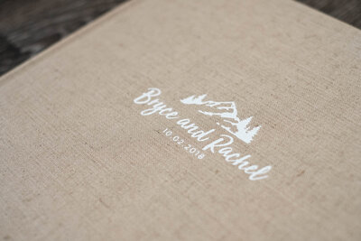 A wedding album with tan cover and debossing in white with mountain logo