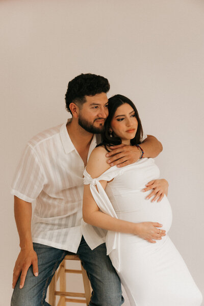 husband hugging wife from behind for studio maternity photoshoot in yuma, arizona