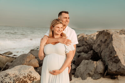 a couple posing at Sandy Hook beach in New Jersey for a mternity photos.