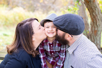 Family love shines through in this Massachusetts portrait by Lorie-Lyn, capturing the joyous embrace of parents kissing their child.