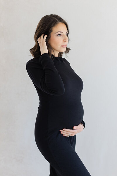 pregnant woman in black dress holding belly maternity pictures 
