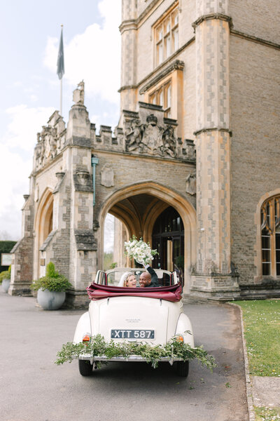 bride and groom laughing in vintage car leaving wedding reception at de vere torthworth court in london, london wedding, english countryside wedding