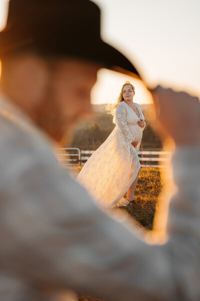 Expecting couple share a kiss at sunset. 