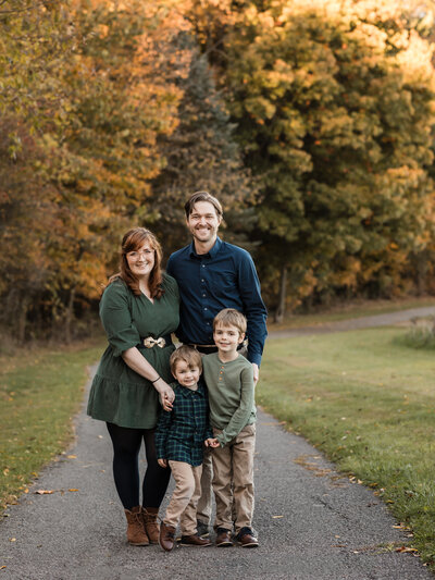 mom and dad holding two sons in park for family portraits 