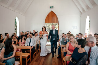 Lorna and Will’s Waiheke Island wedding ceremony at Man O’ War chapel with guests seated, photographed by Zanthe Vorsatz.