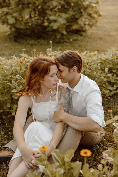 Bride poses in floral wedding dress in a a field while its raining