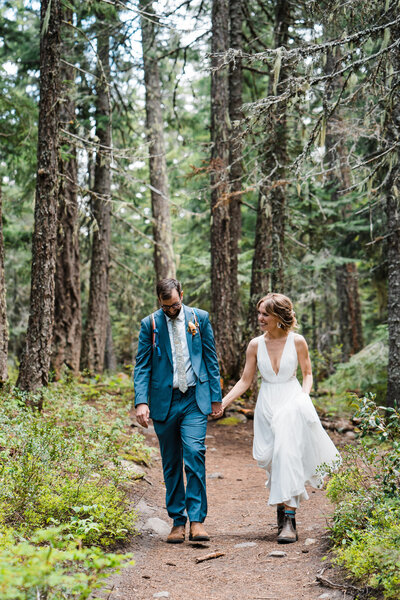 A bride and groom stroll along a mountain trail in Mt Rainier National Park after their Pacific Northwest elopement