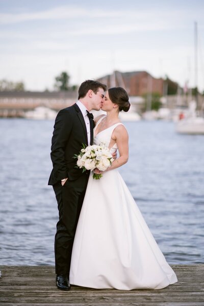 Bride and groom kiss waterfront