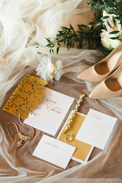 flat lay of wedding invitation, bridal jewelry, and bridal shoes