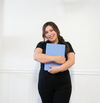 Real Estate SEO Consultant Marie Alaniz  holding a laptop with a blue cover