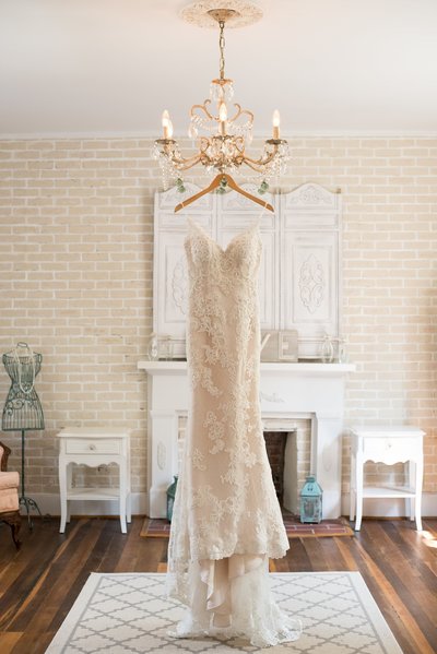 Lace Sweetheart ivory wedding dress hanging from chandelier in bridal suite at Drakewood Farms