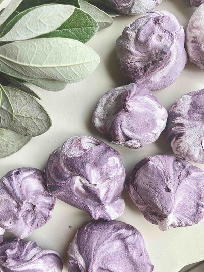 Purple and white swirled meringue cookies on a plate with leave decor.