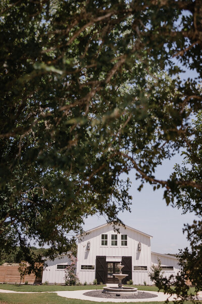 The front of the Barn through the trees at the Posey Meadows Wedding Venue in San Marcos, Texas.
