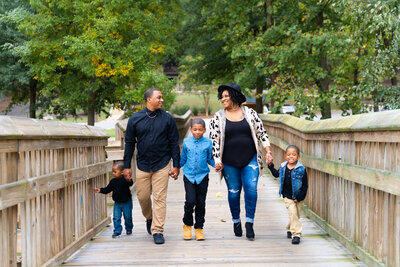 Family of 5 walking on a  wooden bridge