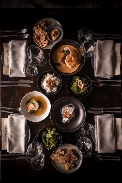Overhead view of a table with multiple plates of food and glassware.