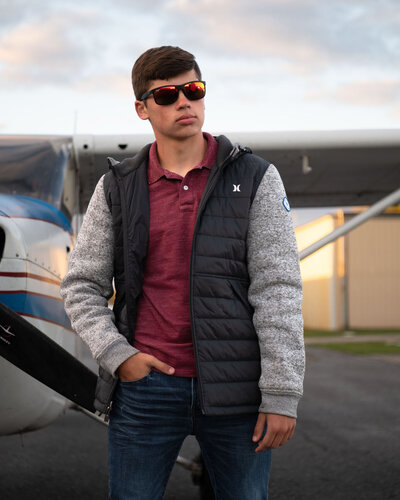 Senior guy in sunglasses in front of  a small airplane