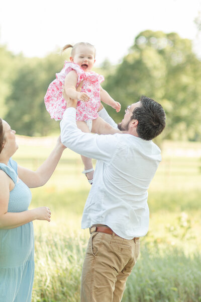 a mother and father playing with their toddler at golden hour