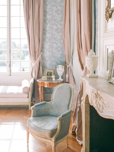 blue room with salmon colored drapes, marble fireplace and light blue occasional chairs