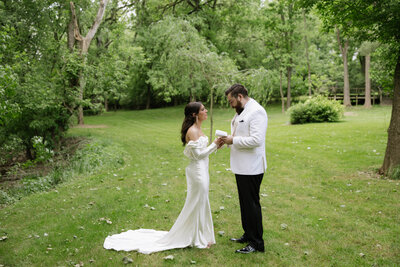 Couple in wedding attire standing forehead to forehead on NJ dock