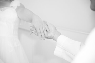 Close-up of groom holding bride's hand with ring