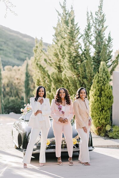 B Astonished Events wedding planners pose in front of a black classic car.