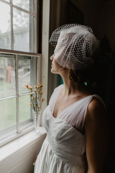 Bride looking over the window on vintage dress