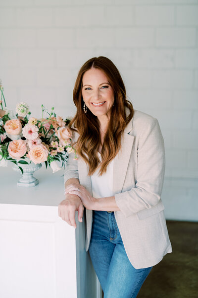 wedding planner Jessica smiling at camera with floral arrangement