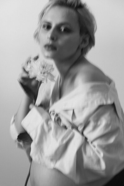 portrait flou avec une fleur d'une future maman pendant sa séance photo grossesse réalisée par studio sensigraphie photographe maternité la tour du pin
