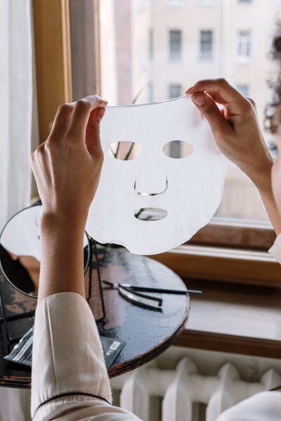 Hands holding up a facial sheet mask