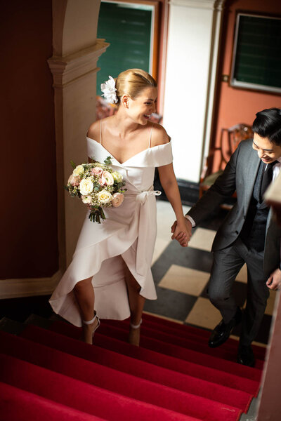bride and groom walking up stairs at registry office