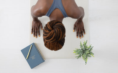 woman in a high plank with closed blue fitness journal laying above her hand