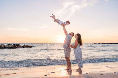 parents toss child in the air during fun family photo shoot at Upham Beach