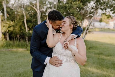 Groom embraces his bride with laughter and tenderness during golden hour in a Colorado field.