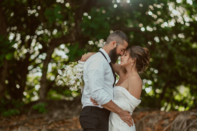 Hawaii elopement bride and groom embrace tightly with Hawaiian sunset in the background