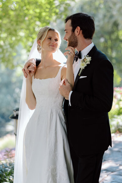 Bride and groom stand outside at Falls Park, and stare endearingly at each other