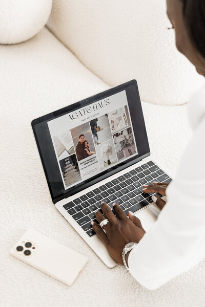 designer working with phone and laptop on couch