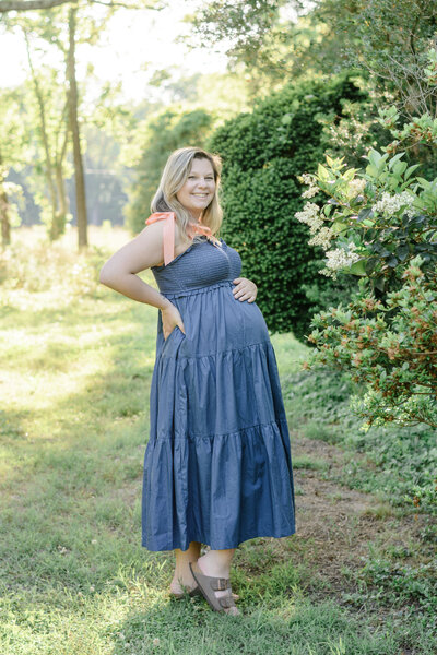 Mom holding her pregnant belly amongst the flowers